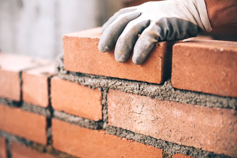 Close-up-of-industrial-bricklayer-installing-bricks-on-construction-site-cm