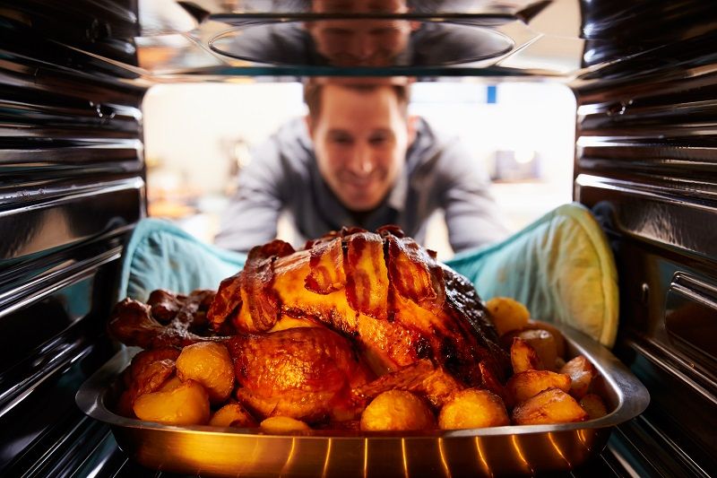 Man-Taking-Roast-Turkey-Out-Of-The-Oven-cm