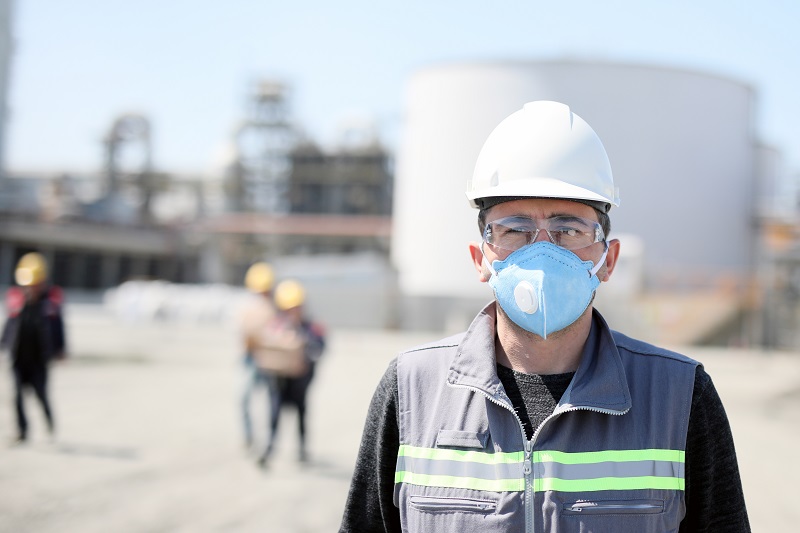 The worker (staff, engineer) protects himself from covid-19 (coronavirus) with a protective mask in the construction site.