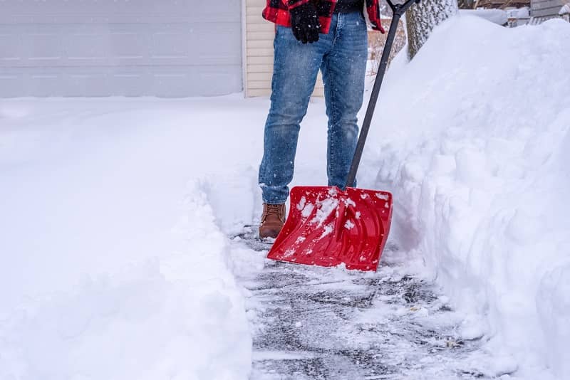 Man shoveling deep snow by hand with a red snow shovel-cm