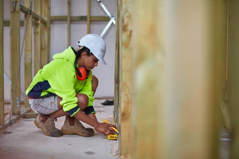 Female worker using tape measure at site-cm