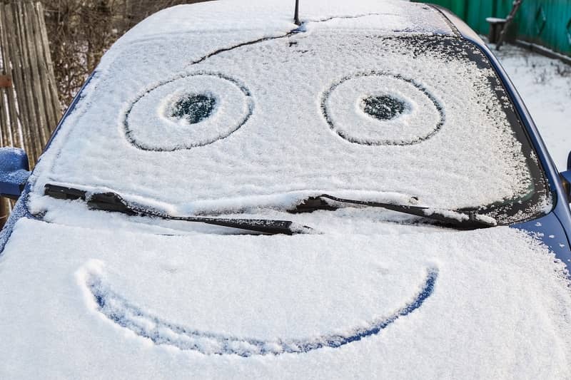 Snow-covered car with smiley-cm