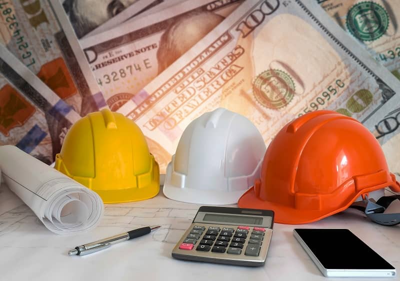 Architectural blueprint with safety helmet and tools on blur dollar money background-cm