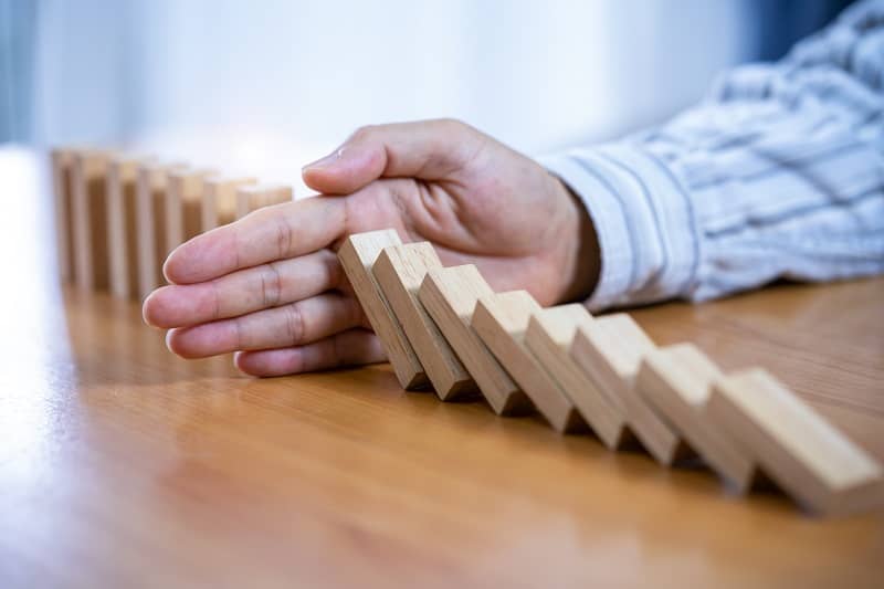 Businessman Stop Domino Effect. Risk Management and Insurance Concept -cm