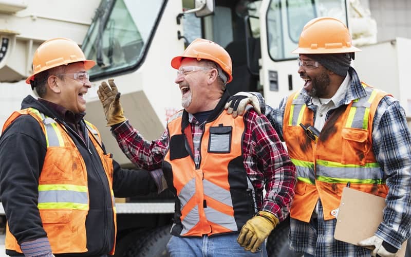 Three multiracial construction workers laughing-cm