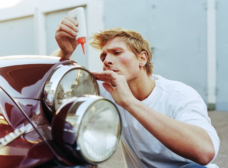 Man fixing car headlight, outdoors, close-up-cm